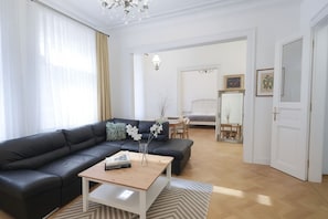 Ein modernes Wohnzimmer mit einer schwarzen Ledersofa, einem Holztisch und einem Essbereich inklusive Tisch und Stühlen.