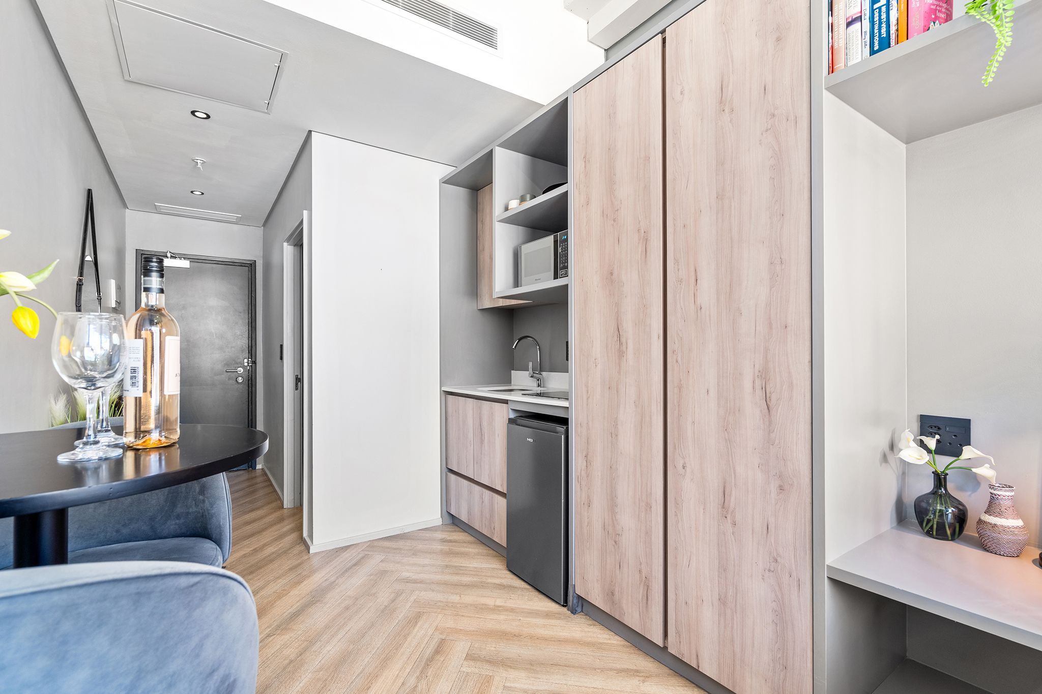 A modern kitchen with wooden cabinets, a built-in microwave, and a black refrigerator.