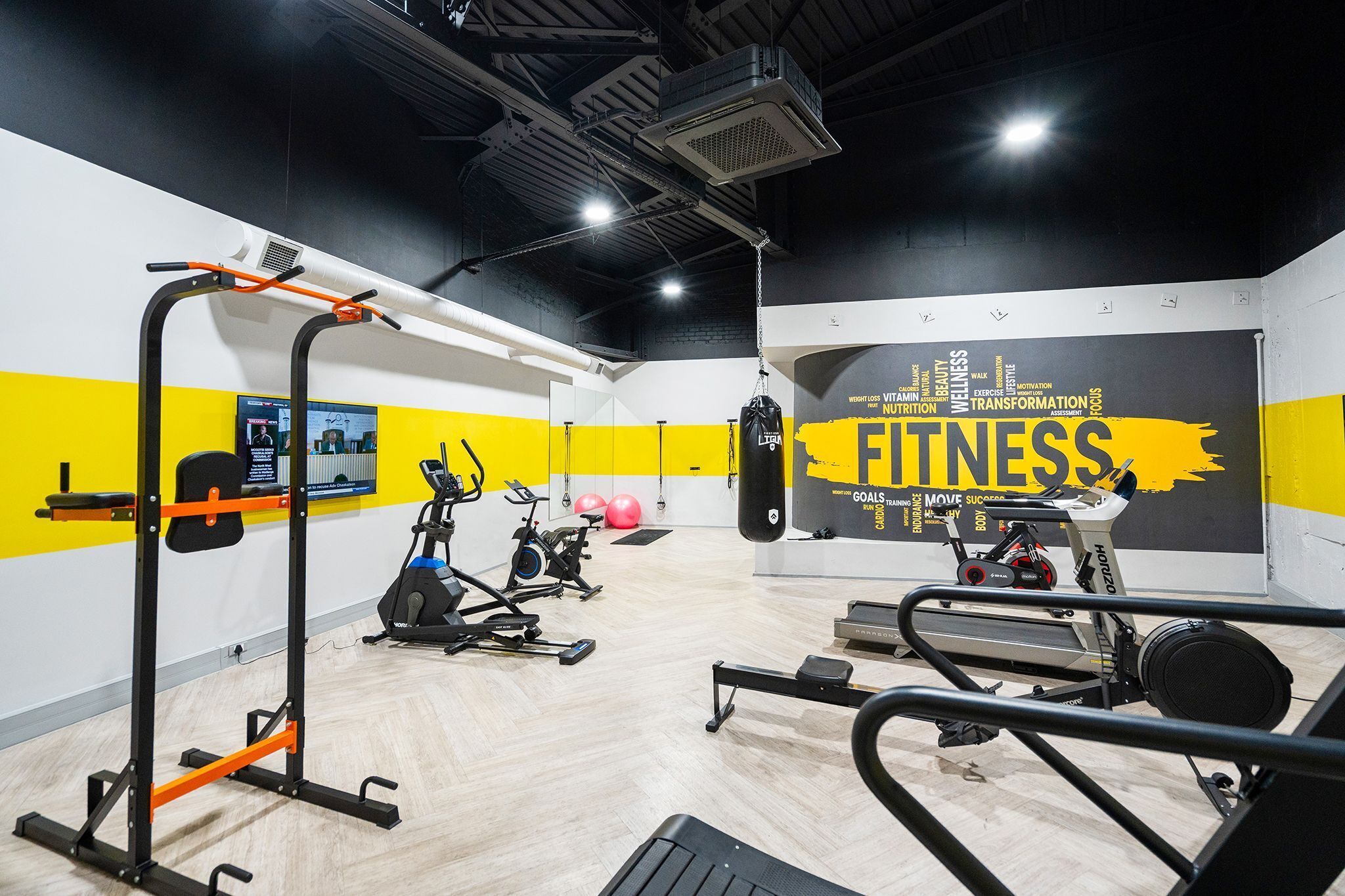 Une salle de sport équipée de matériel d’exercice, d’un sac de frappe et dont les murs sont ornés de citations motivantes.