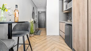 Una cocina moderna con lavavajillas integrado, un comedor con mesa y sillas, y un pasillo que lleva a una puerta.