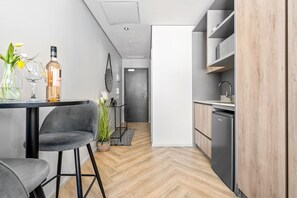 Eine moderne Küche mit integriertem Geschirrspüler, ein Essbereich mit Tisch und Stühlen sowie ein Flur zu einer Tür.