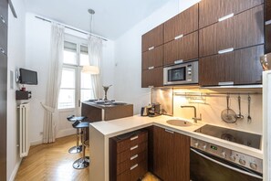 Eine kompakte Küche mit Mikrowelle, Backofen und Barhocker.