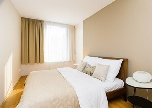 A hotel room with a bed, a bedside table, and a window with curtains. - Contemporary Residence in Trendy Karlín District (Prague 8)