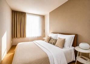 A bedroom with a bed, bedside table, and a window with curtains. - Contemporary flat in a trendy Karlin District (Prague 8)