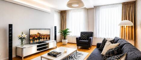Ein modernes Wohnzimmer mit Flachbildfernseher, einer Couch, einem Couchtisch und einem Topf mit Pflanze.