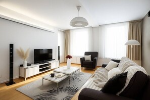 A modern living room with a flat-screen TV, a sofa, a coffee table, and a chair. - Contemporary Residence in Trendy Karlín District (Prague 8)