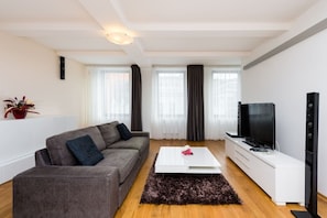 Ein modernes Wohnzimmer mit einem grauen Sofa, einem weißen Couchtisch, einem Fernseher und einer Stereoanlage.
