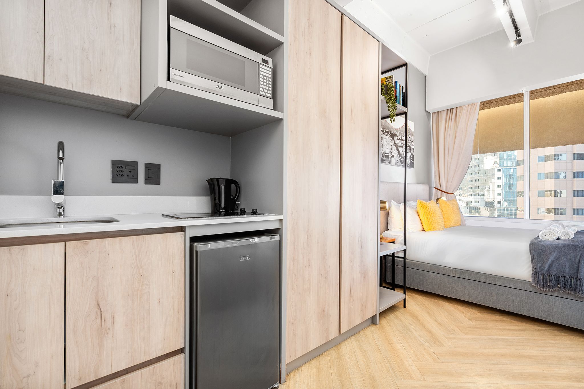 Una kitchenette moderna equipada con microondas, cafetera y lavavajillas integrado.