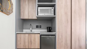 A modern kitchen with wooden cabinets, a built-in microwave, a coffee maker, and a dishwasher. - One Thibault 1609 (Cape Town)