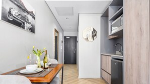 A modern kitchen with a built-in dishwasher, a dining area with a table set for two, and a hallway leading to a door. - One Thibault 1609 (Cape Town)