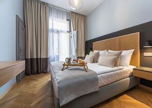 Una habitación de hotel moderna con una cama grande, cabecera de madera y una bandeja de desayuno en la cama.