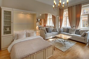 Ein Hotelzimmer mit Bett, Sofa, Couchtisch und Blick auf die Stadt.