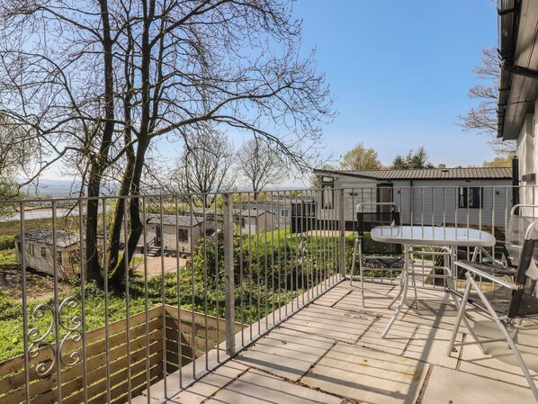 A residential area with a metal fence, a wooden bench, and a small table. - Beacon Fell Cottage 1 (Preston)