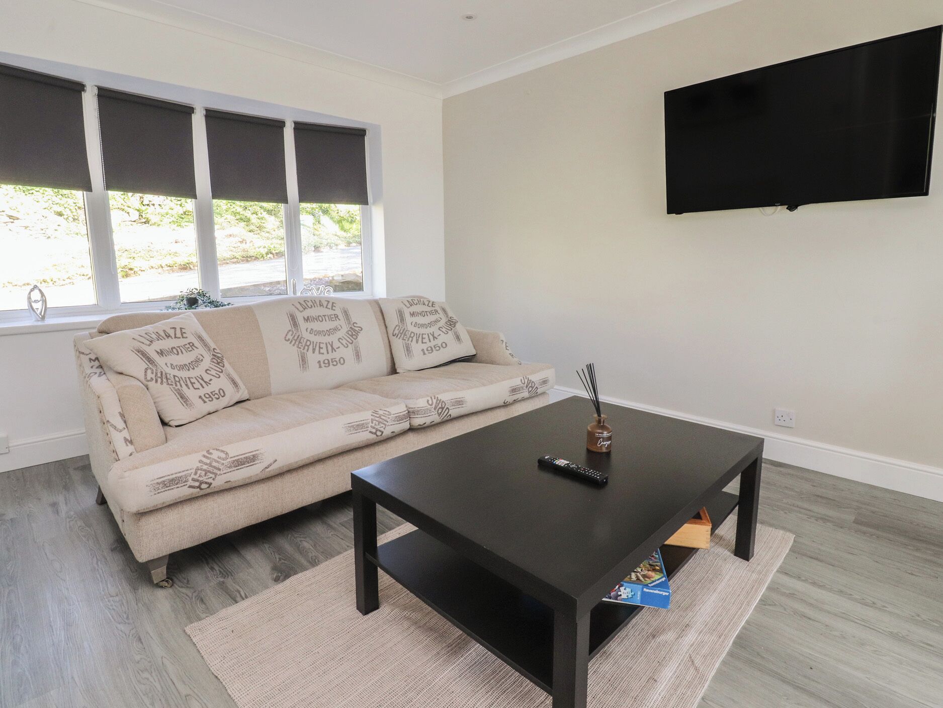 Una sala de estar con sofá, mesa de centro, televisor y ventana con persianas.