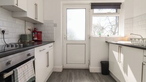 Eine Küche mit weißen Schränken, einem Herd, einer Spüle und einem Fenster mit Blick.