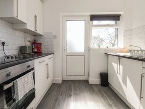 A kitchen with white cabinets, a stove, a sink, and a window with a view. - Beacon Fell Cottage 1 (Preston)