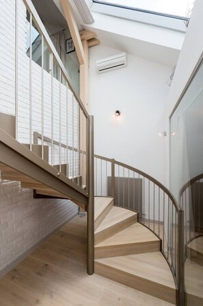 A modern staircase with glass railings, a wooden floor, and a white wall with a window. - Old Town 2-BR Loft with Panoramic Prague Castle Views (Praha 1)