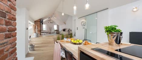 A modern kitchen with a wooden countertop, a sink, and a dining area with a table set for two.