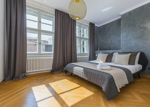 Ein Schlafzimmer mit Bett, Vorhängen, Heizkörper und Fenster.