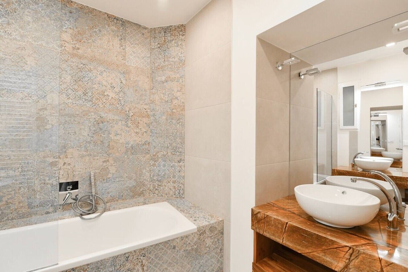 Een moderne badkamer met een vrijstaand bad, een grote spiegel en een wastafelmeubel met een wastafel.