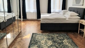 Ein Schlafzimmer mit einem Bett, einem Nachttisch, einem Spiegel und einem Fenster mit Vorhängen.