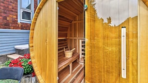 Uma sauna de madeira com um banco interior, uma porta e uma janela.