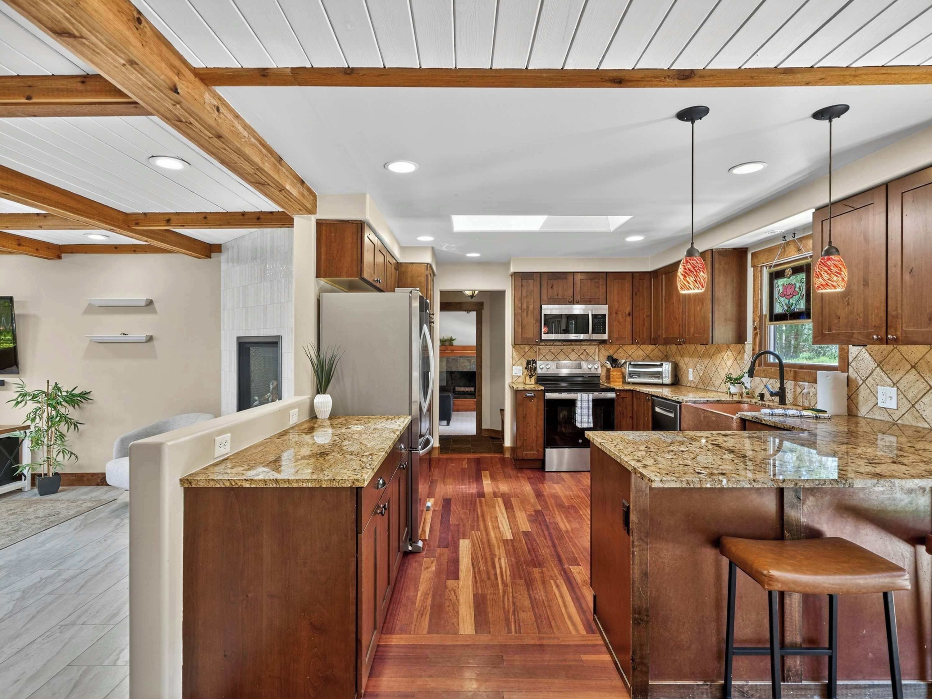 A modern kitchen with wooden cabinets, granite countertops, and a central island.
