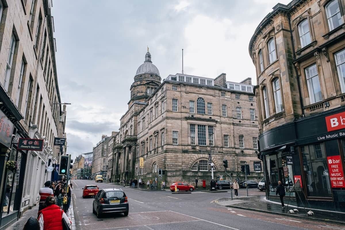 A street view with historic buildings, a prominent dome, and a bar with live music.