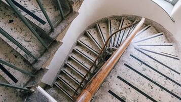 A spiral staircase with a wooden handrail and metal balusters, leading to an upper floor.