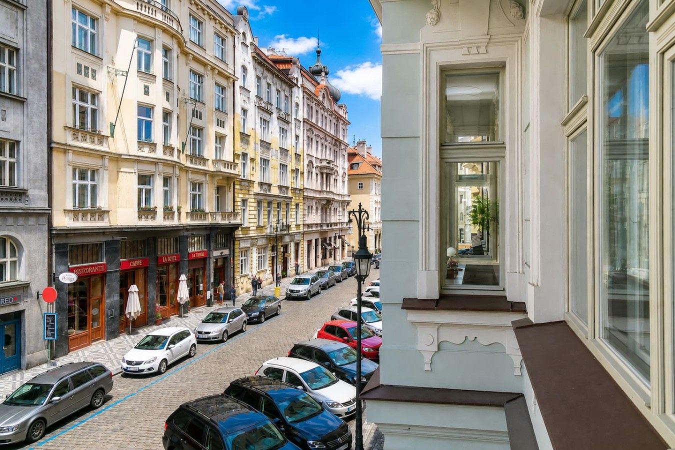 Een straatbeeld met geparkeerde auto's en een gebouw met een balkon.