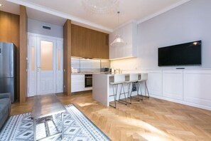 A modern kitchen with white cabinets, a built-in oven, and a large island with bar stools. - Luxury One-Bedroom Retreat in Old Town (Praha 1)