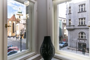 A window with a view of a street, a black vase, and a building with a sign. - Luxury One-Bedroom Retreat in Old Town (Praha 1)