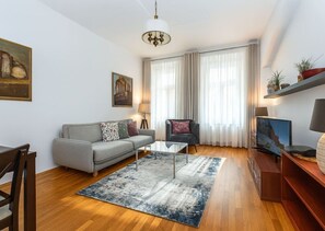 Ein modernes Wohnzimmer mit einer Couch, einem Couchtisch, einem Fernseher und einem Kronleuchter.