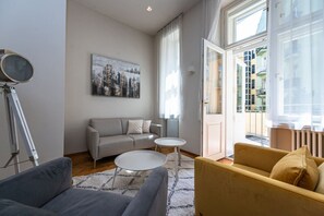 Ein modernes Wohnzimmer mit einer Couch, zwei Sesseln, einem Couchtisch und einem Gemälde an der Wand.