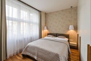 Ein Schlafzimmer mit einem Bett, Vorhängen, Wandlampen und Holzboden.