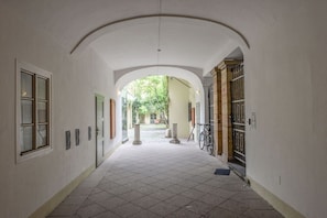 Ein Korridor mit Fliesenboden, gewölbter Decke und Blick auf einen Garten.