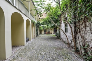 Ein Innenhof mit Kopfsteinpflaster, Bögen und einem Gebäude mit efeuüberwachsenen Mauern.