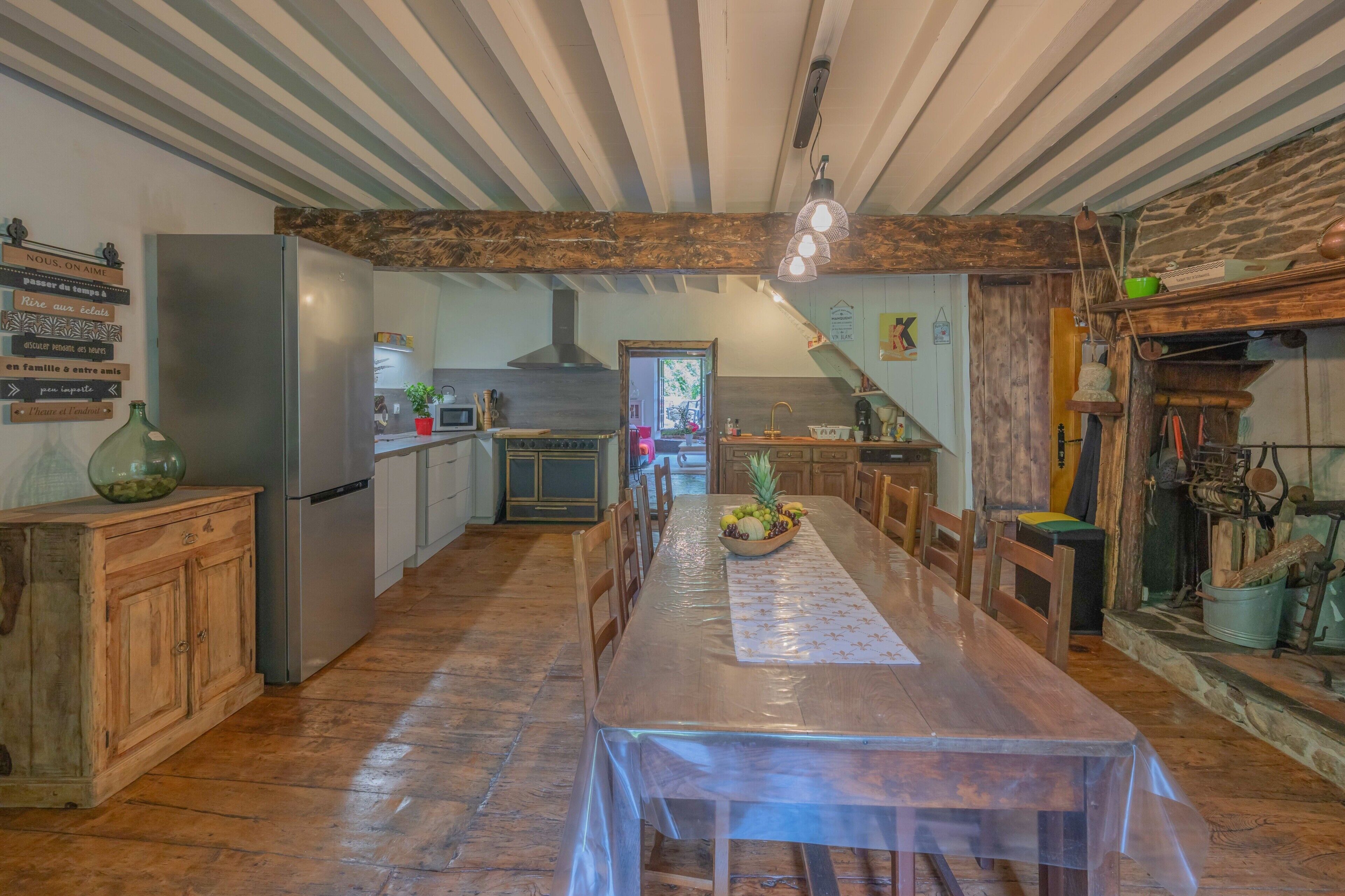 Una cocina con una mesa de madera, un refrigerador y una zona de comedor.