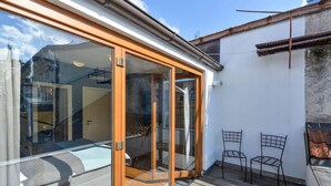 A residential space with a sliding glass door leading to a balcony, a small outdoor seating area with two chairs, and a visible staircase. - Designer Two-Bedroom Loft with Terrace in Old Town (Praha 1)