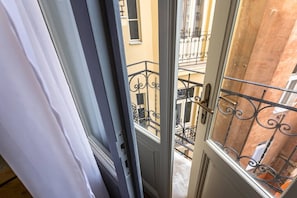 Blick durch eine Tür mit einem Metall-Balkonläufer, einem Holztürrahmen und einem Fenster mit Metallgitter.