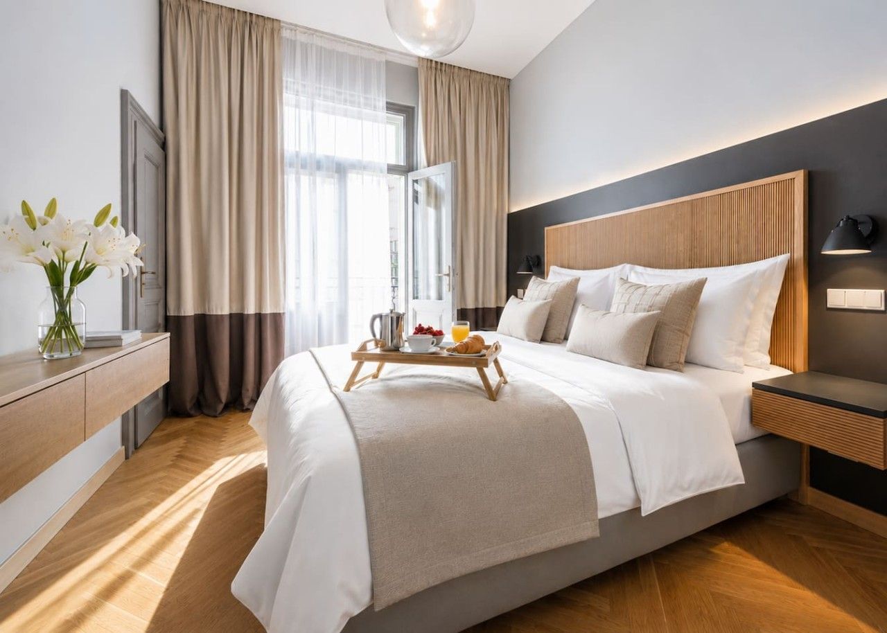 Une chambre d’hôtel moderne avec un grand lit, une table de chevet et un plateau contenant des articles pour le petit-déjeuner.