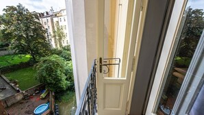 A balcony with a view of a garden and a building across the street. - Luxury Two-Bedroom Residence in Vinohrady (Praha 2)