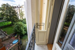 Ein Balkon mit Blick auf einen Garten und ein Gebäude gegenüber.