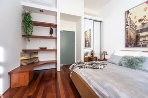 A modern bedroom with a bed, a wooden bench, a plant, and a painting. - Spacious Old Town Square Two-Bedroom Residence (Praha 1)