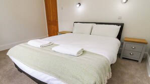 A neatly made bed with a patterned bedspread, two pillows, and a folded towel. - 6 Hazel Moor (Blackburn)