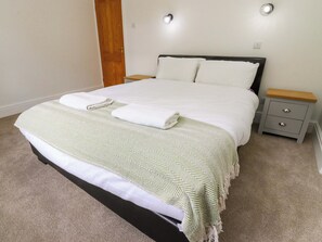 A neatly made bed with a patterned bedspread, two pillows, and a folded towel. - 6 Hazel Moor (Blackburn)