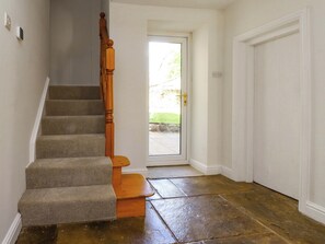 A staircase with carpeted steps and wooden handrails, leading to a door with a glass panel.