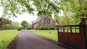 A church with a paved driveway leading to a gated entrance.