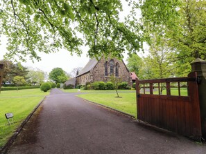 A church with a paved driveway leading to a gated entrance.