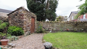 A stone building with a wooden door, surrounded by a stone wall and a grassy area. - 6 Hazel Moor (Blackburn)